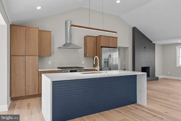 a kitchen with stainless steel appliances granite countertop a refrigerator a oven and white cabinets with wooden floors