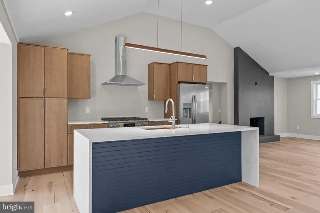 a kitchen with stainless steel appliances granite countertop a refrigerator a oven and white cabinets with wooden floors