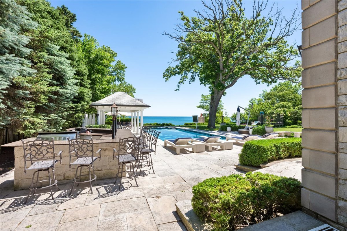 319 Sheridan Road Winnetka, IL 60093 - Photo 17 of 81 a view of a patio with table and chairs under an umbrella with large trees
