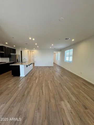 a view of an empty room with wooden floor and kitchen