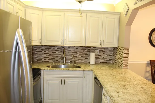 a kitchen with a granite countertop sink and a refrigerator