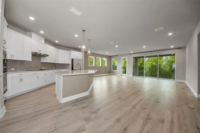 a large kitchen with stainless steel appliances granite countertop a large center island attached withe living room