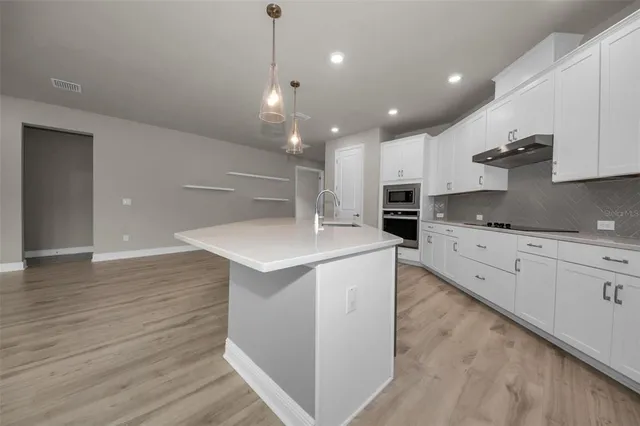a large kitchen with stainless steel appliances kitchen island a large counter top and a stove top oven