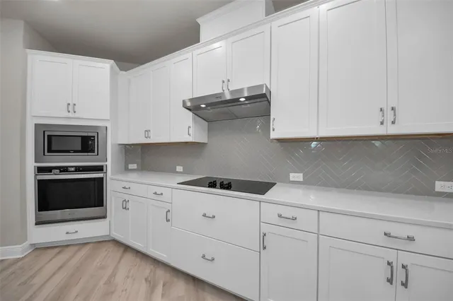 a kitchen with stainless steel appliances granite countertop white cabinets granite counter tops and a wooden floors