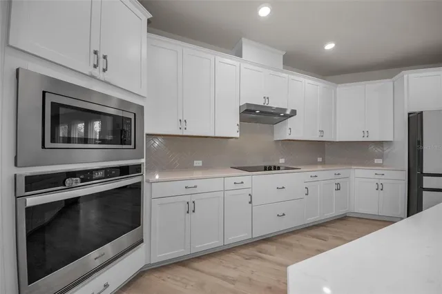 a kitchen with granite countertop white cabinets stainless steel appliances and sink