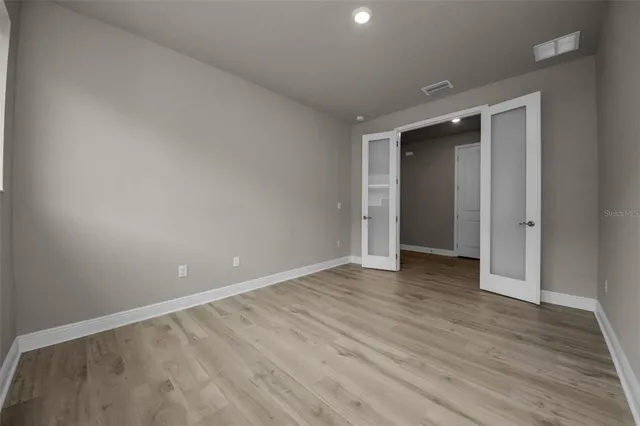 a view of an empty room with wooden floor and closet