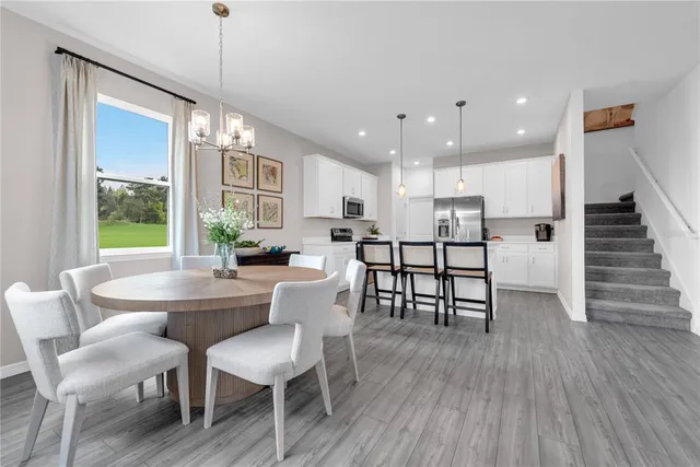 a kitchen with stainless steel appliances a dining table chairs stove refrigerator and cabinets