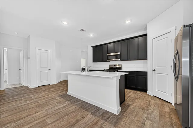 a kitchen with granite countertop a refrigerator stove top oven and sink