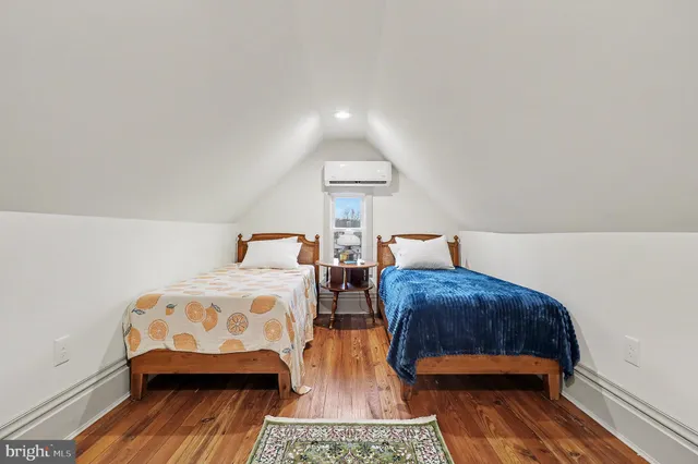 a bedroom with two beds and wooden floor