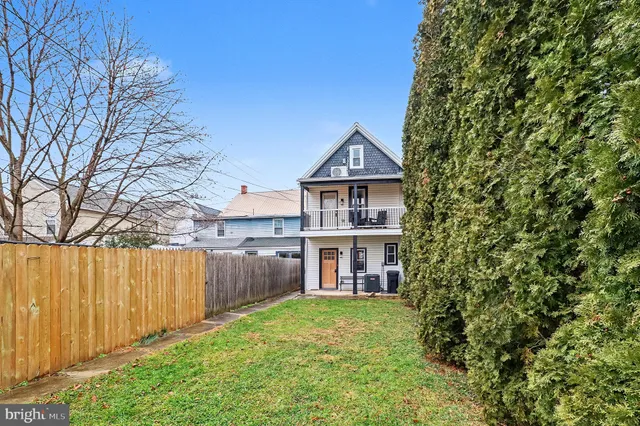 a view of a house with a yard and wooden fence