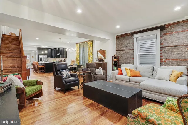 a living room with furniture kitchen view and a large window