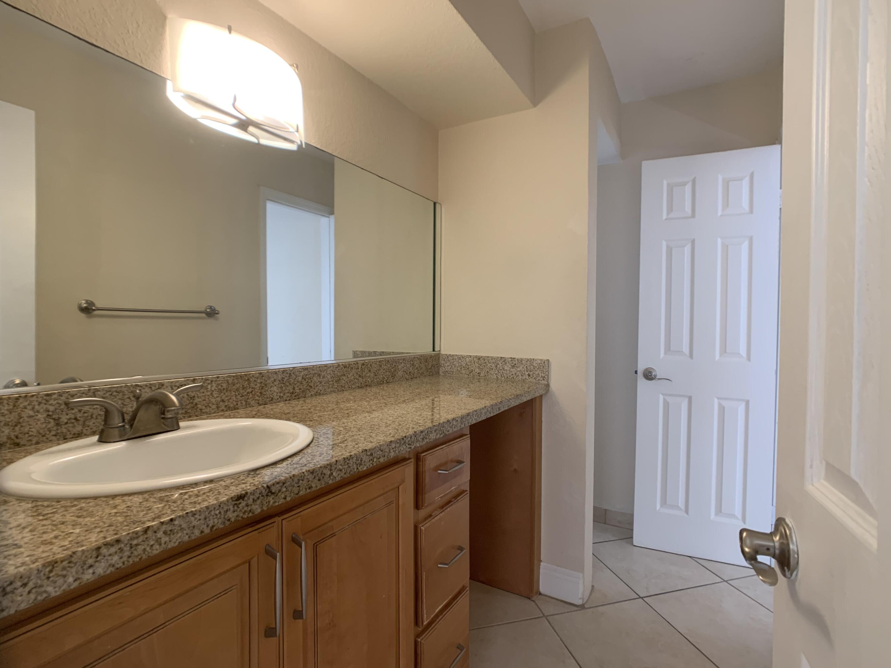 8601 Southwest 94th Street, Unit 201W Miami, FL 33156 - Photo 6 of 14 a bathroom with a granite countertop sink and a mirror