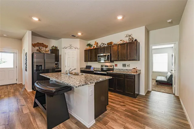 a large kitchen with stainless steel appliances granite countertop a lot of counter space and wooden floor