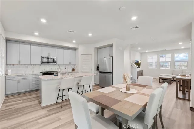 a kitchen with a dining table chairs wooden floor appliances and cabinets