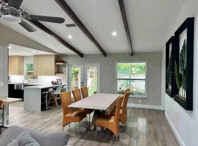 a dining room with wooden floor a chandelier a wooden table and chairs