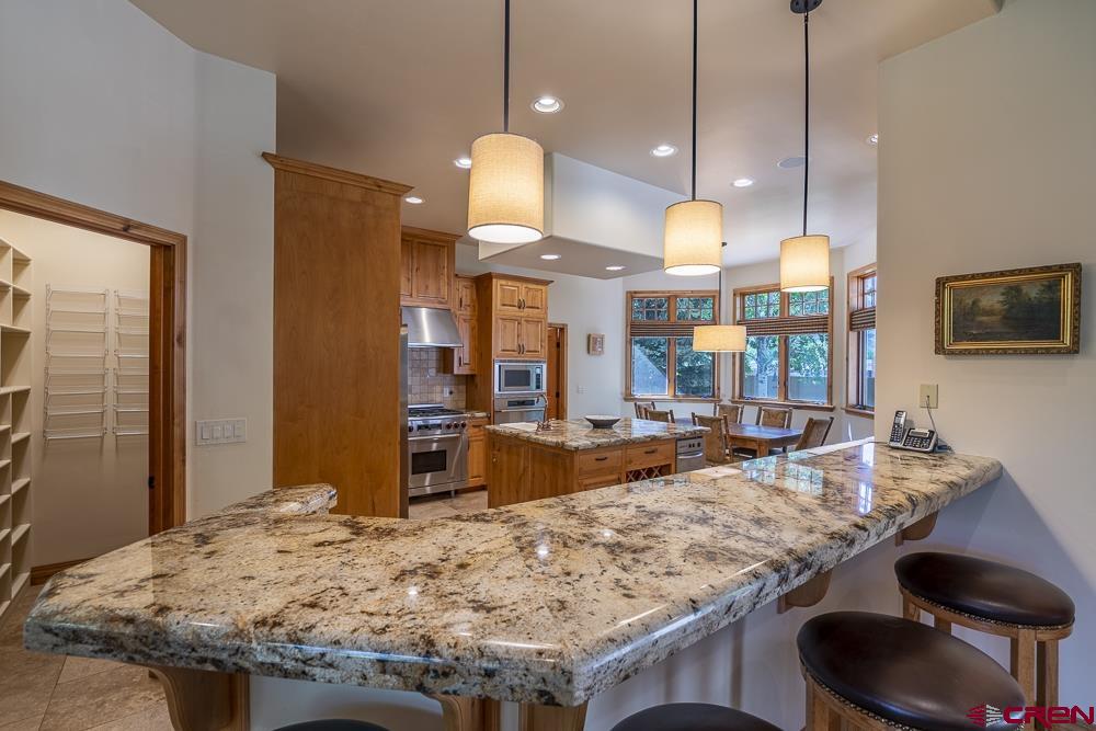 970 Red Rock Road Durango, CO 81301 - Photo 15 of 35 a kitchen island with granite countertop a sink a stove and a wooden floor