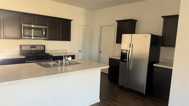 a kitchen with stainless steel appliances granite countertop a refrigerator a stove top oven a sink and dishwasher