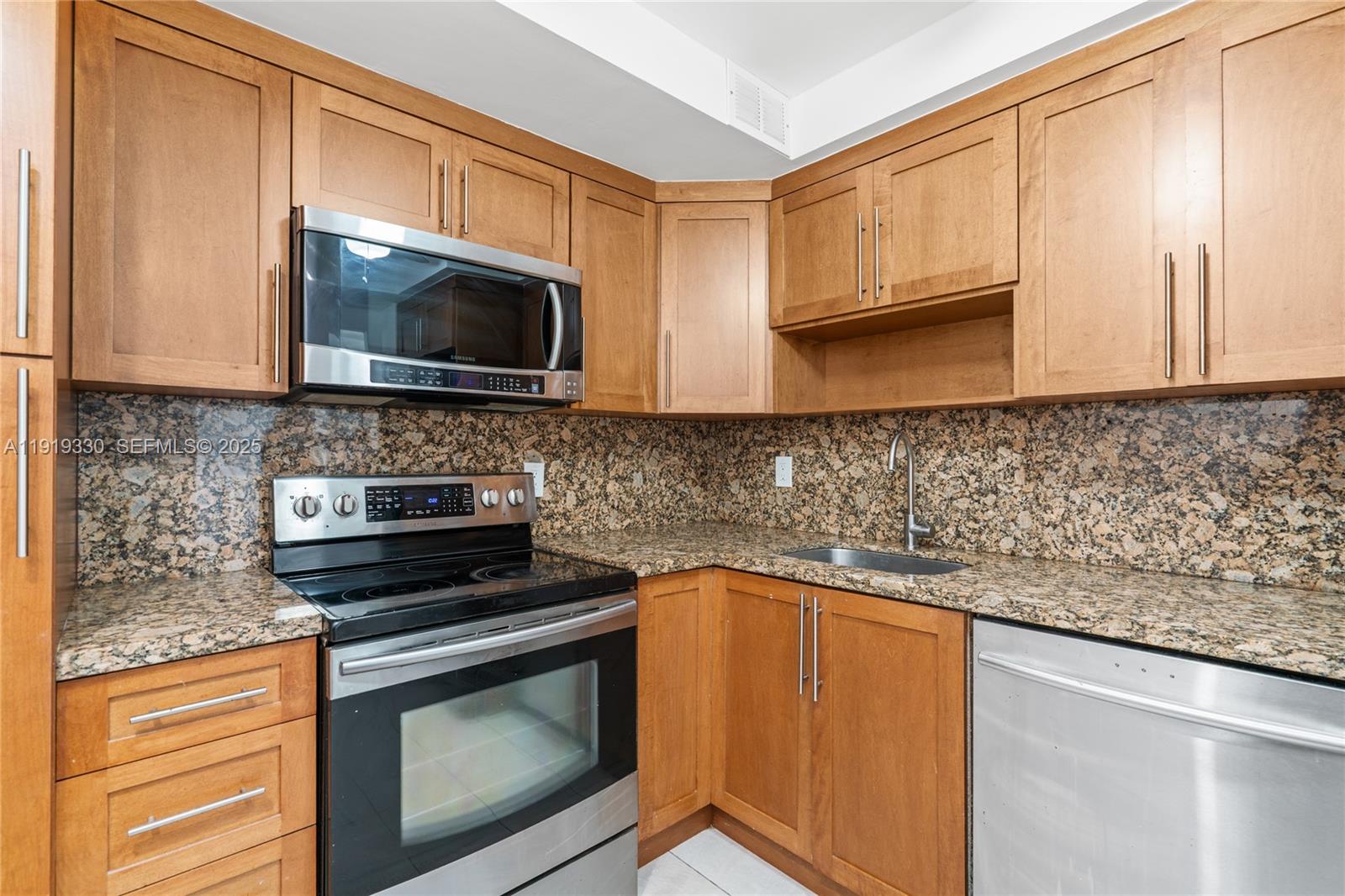 4101 Pine Tree Drive, Unit 1112 Miami Beach, FL 33140 - Photo 8 of 62 a kitchen with granite countertop a stove top oven microwave and cabinets