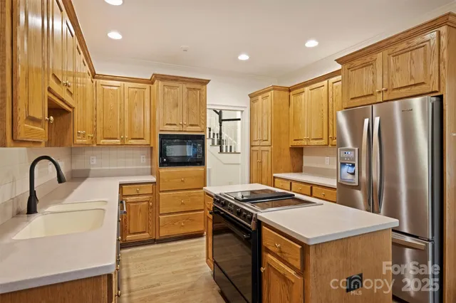 a kitchen with stainless steel appliances a refrigerator a sink a stove and cabinets