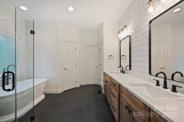 a spacious bathroom with a double vanity sink a mirror and a bathtub