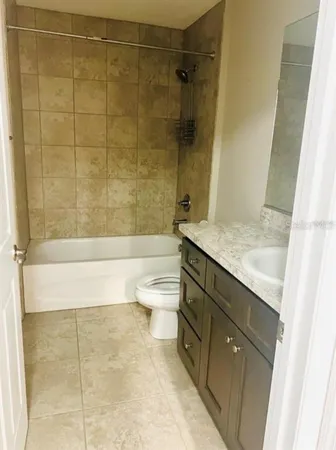 a bathroom with a granite countertop bathtub shower sink and toilet