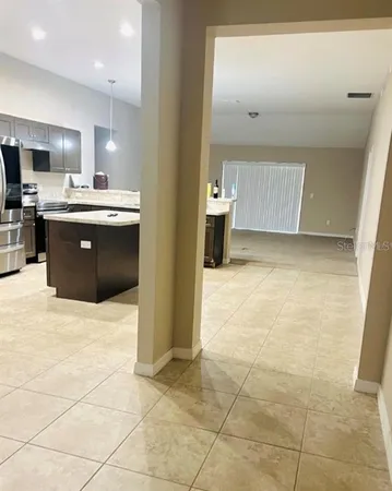 a view of kitchen with stainless steel appliances kitchen island granite countertop a sink and cabinets