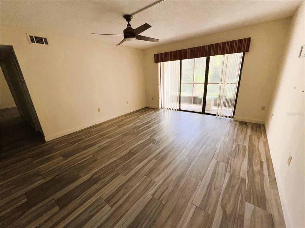 1372 Pine Ridge Circle East, Unit F1 Tarpon Springs, FL 34688 - Photo 6 of 21 a view of an empty room with wooden floor and a window