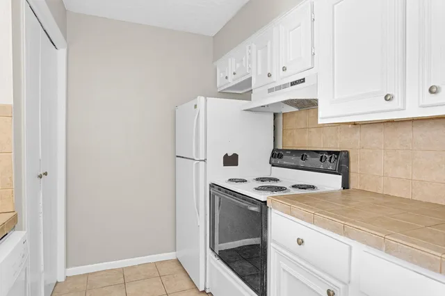 a kitchen with stainless steel appliances granite countertop a stove a refrigerator and a white cabinets