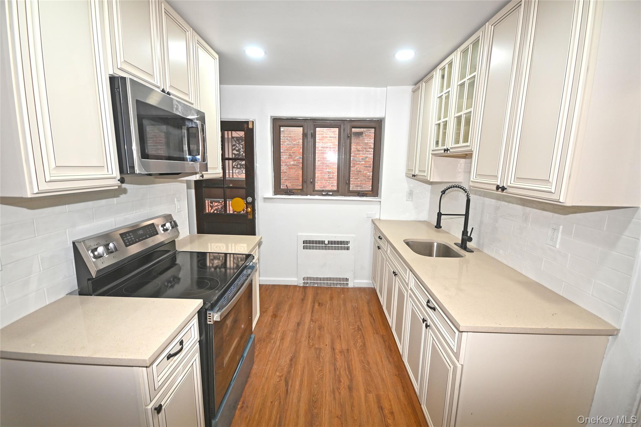112-13 178th Street Queens, NY 11433 - Photo 13 of 28 Kitchen with backsplash, stainless steel appliances, glass insert cabinets, light stone counters, and recessed lighting
