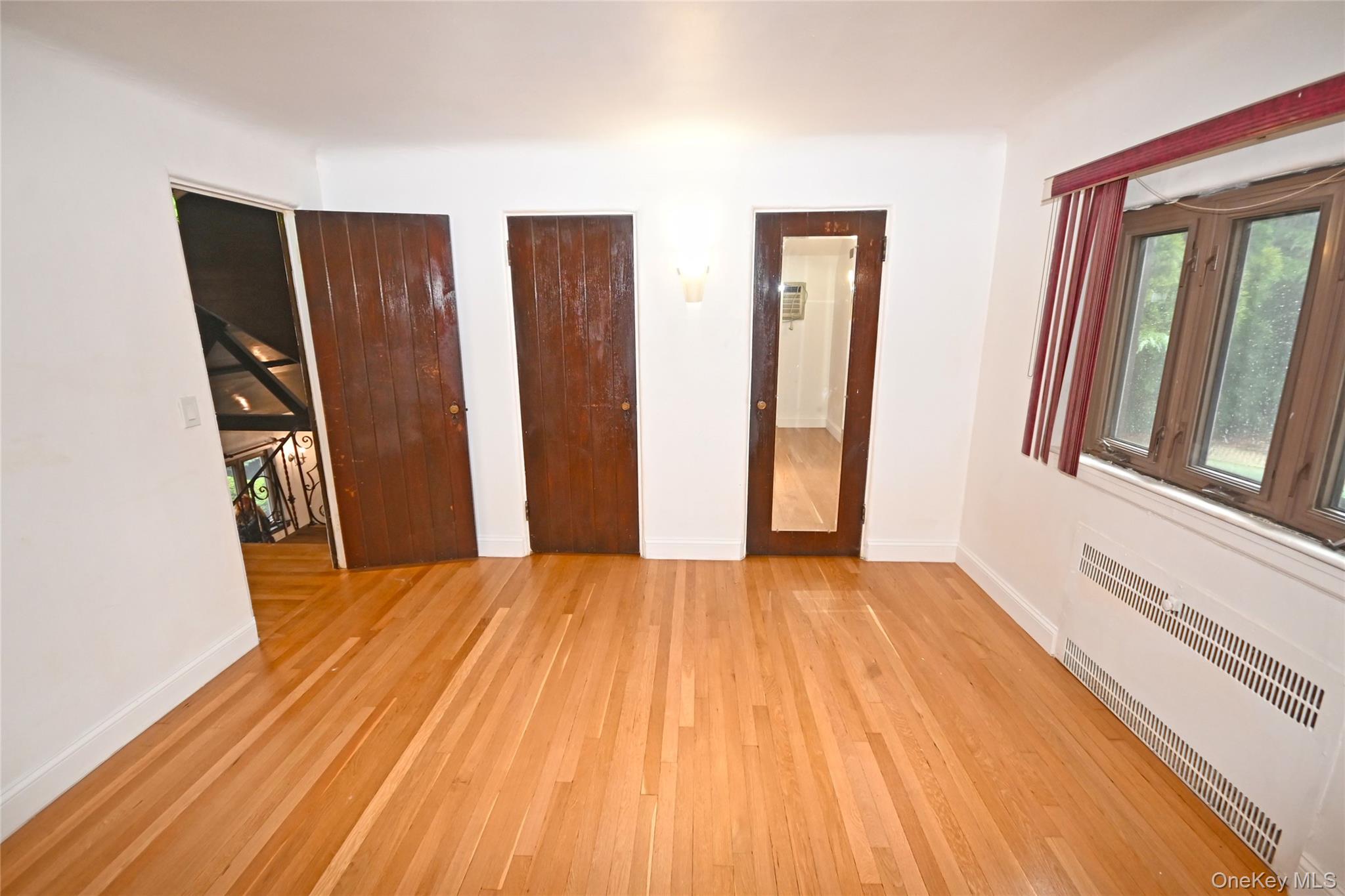 112-13 178th Street Queens, NY 11433 - Photo 17 of 28 Unfurnished bedroom featuring radiator, light wood finished floors, and two closets