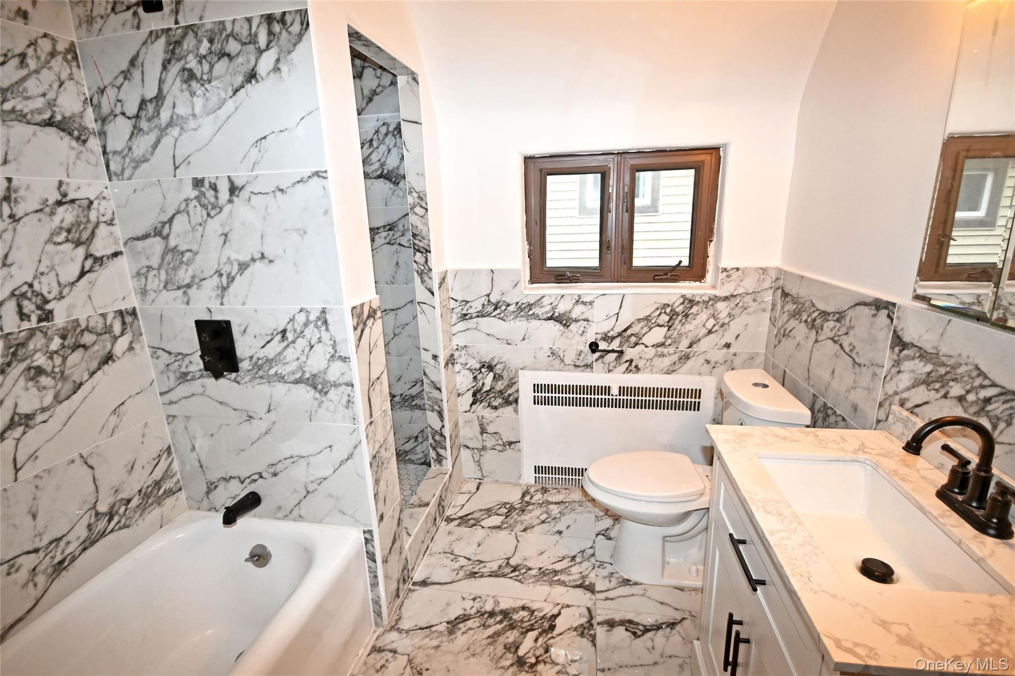 112-13 178th Street Queens, NY 11433 - Photo 19 of 28 Bathroom featuring vanity, radiator, tile walls, and light marble finish floors