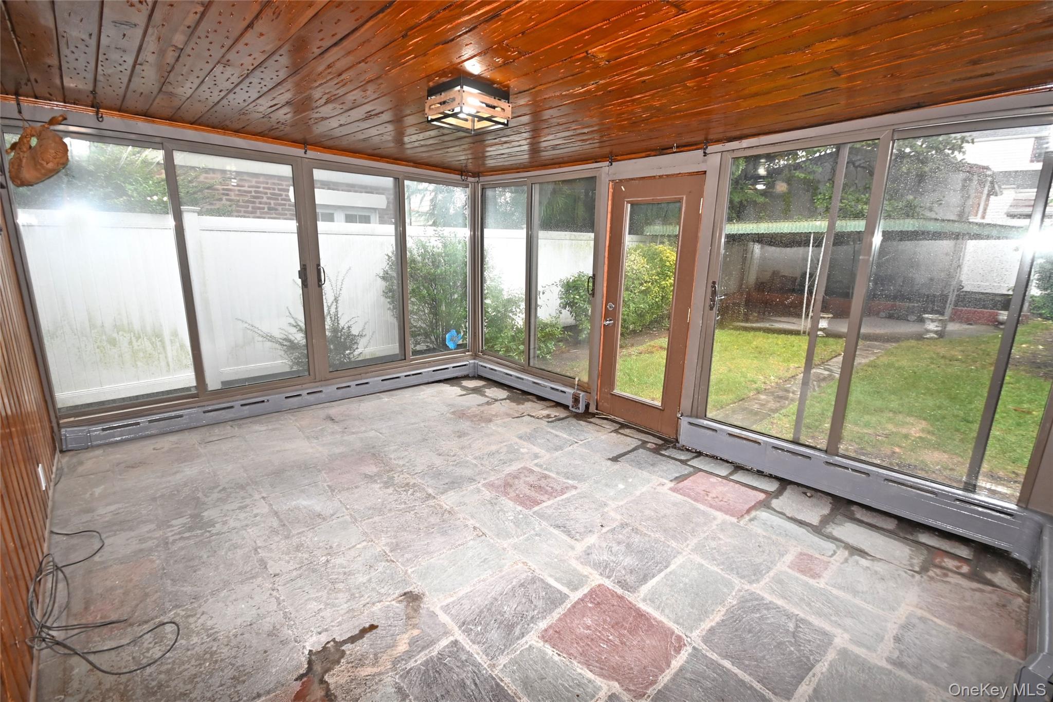 112-13 178th Street Queens, NY 11433 - Photo 22 of 28 Unfurnished sunroom featuring stone tile floors, healthy amount of natural light, a baseboard radiator, and wooden ceiling