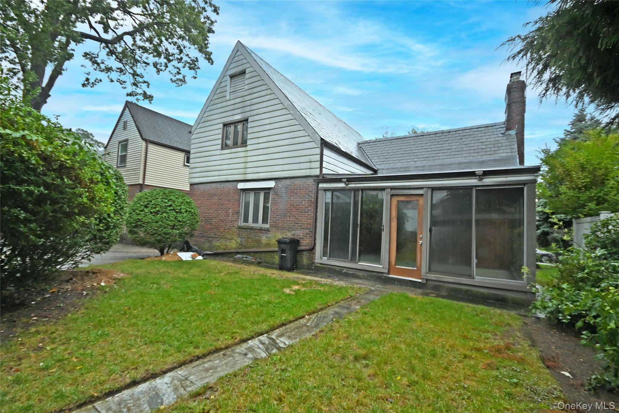 112-13 178th Street Queens, NY 11433 - Photo 25 of 28 Back of property featuring brick siding, a lawn, a chimney, and a sunroom