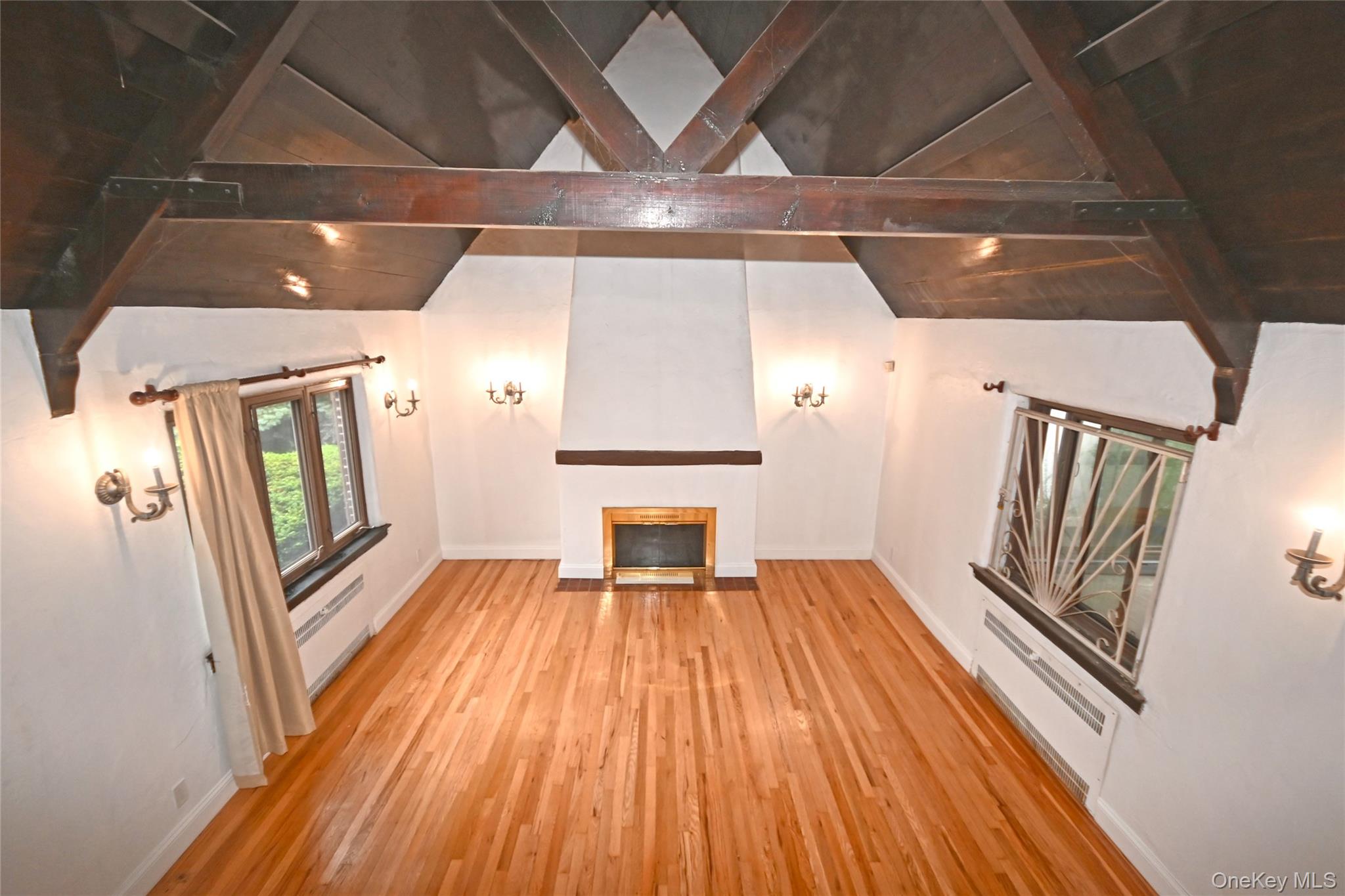 112-13 178th Street Queens, NY 11433 - Photo 3 of 28 Unfurnished living room featuring a baseboard heating unit, wood finished floors, and a fireplace