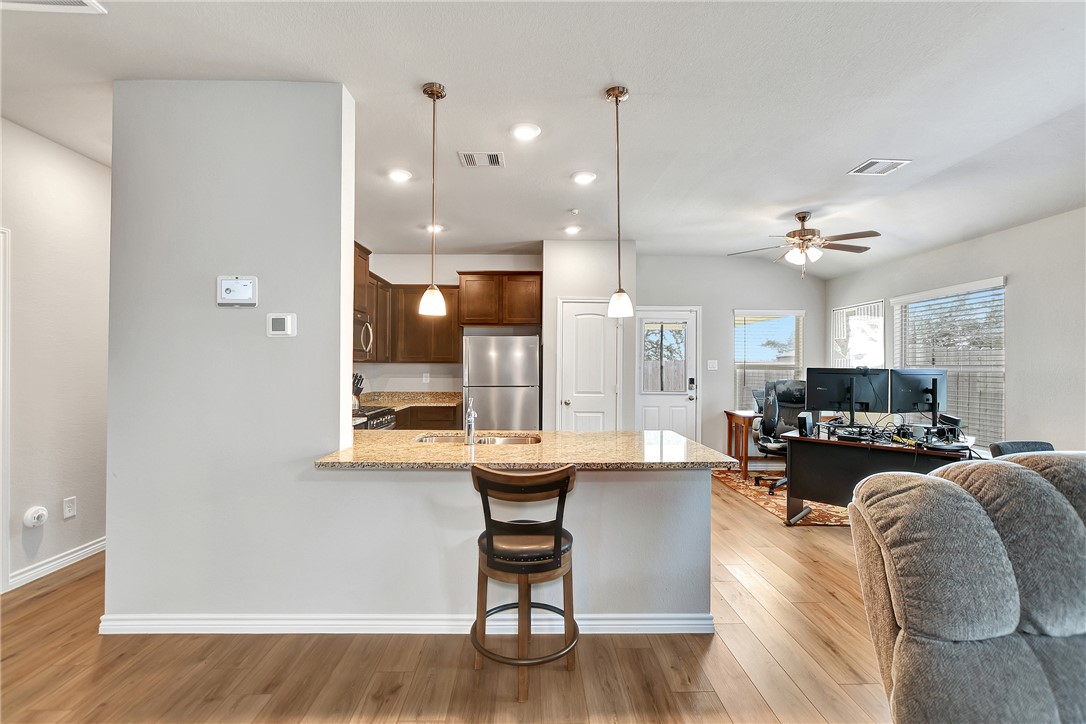 909 Davy Street Brenham, TX 77833 - Photo 32 of 35 Kitchen featuring open floor plan, hanging light fixtures, light wood-style flooring, and light stone counters
