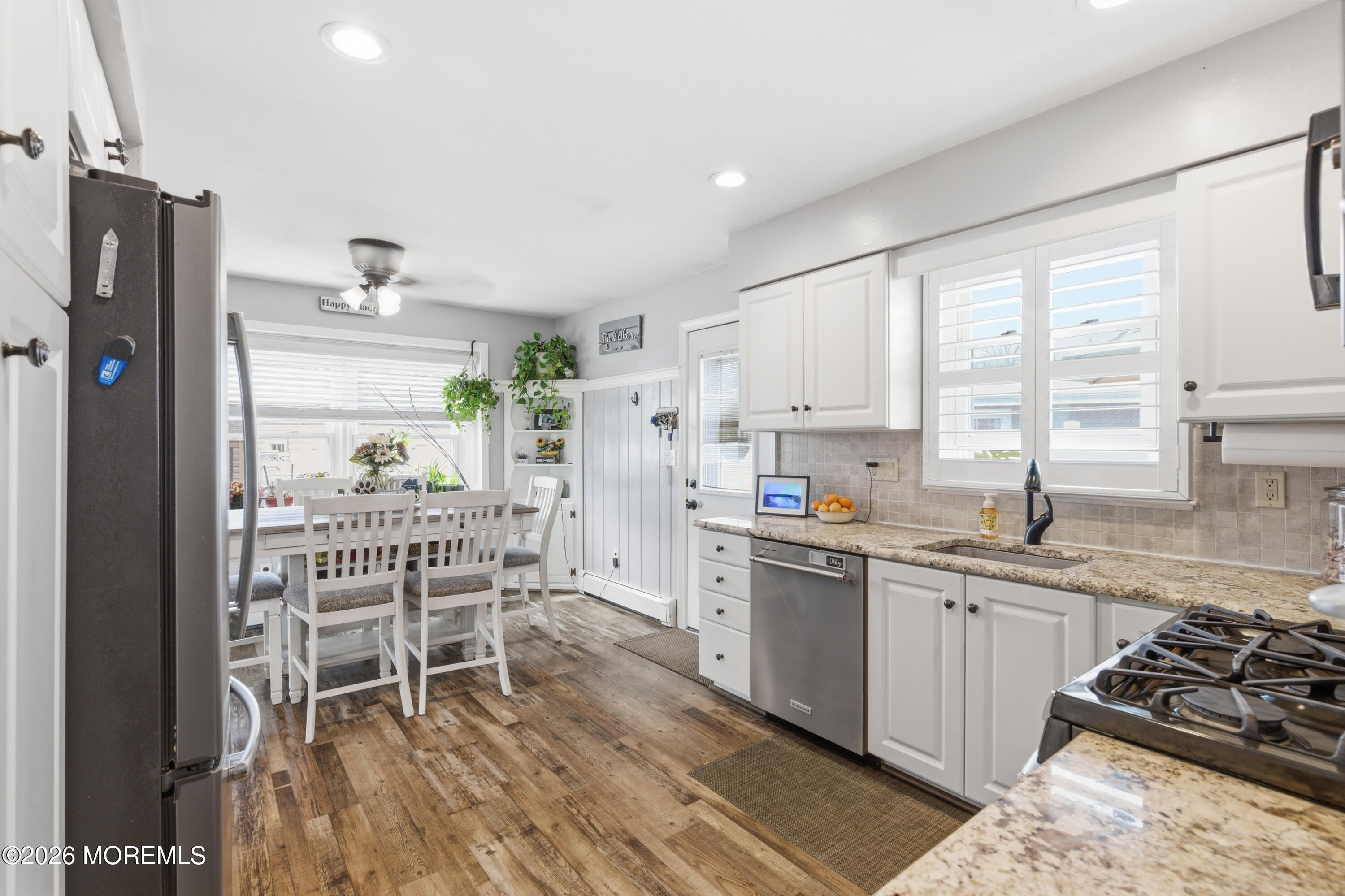 1155 Lockhart Lane Point Pleasant, NJ 08742 - Photo 17 of 33 a kitchen with stainless steel appliances granite countertop a stove top oven a sink dishwasher a dining table and chairs with wooden floor