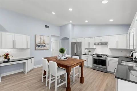 a kitchen with granite countertop kitchen island stainless steel appliances a stove a sink a refrigerator cabinets and a dining table