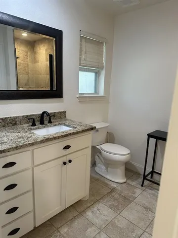 a bathroom with a granite countertop toilet sink and mirror
