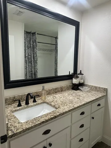 a bathroom with a granite countertop sink and a mirror