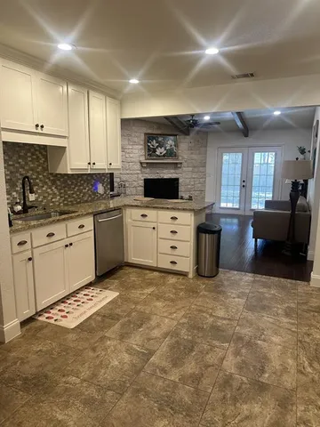 a large kitchen with granite countertop a stove top oven a sink a dining table and chairs