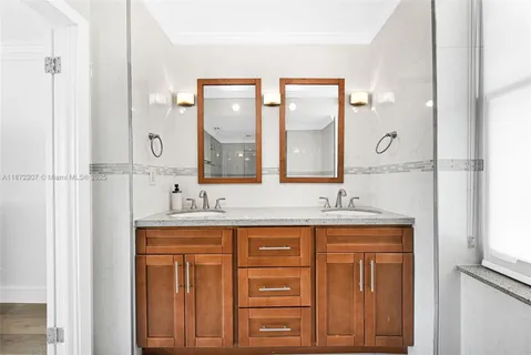 a bathroom with a granite countertop sink a mirror and a shower