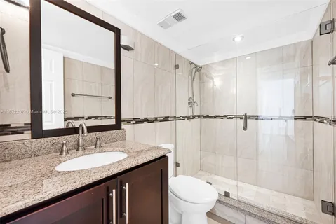 a bathroom with a granite countertop sink toilet and shower