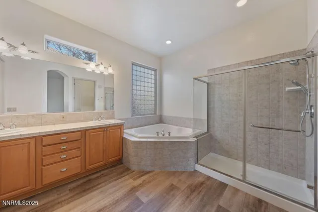 a spacious bathroom with a granite countertop double vanity sink a mirror and a shower