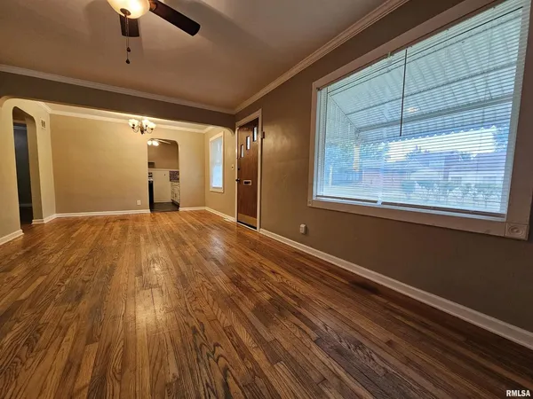 a view of an empty room with a window and wooden floor