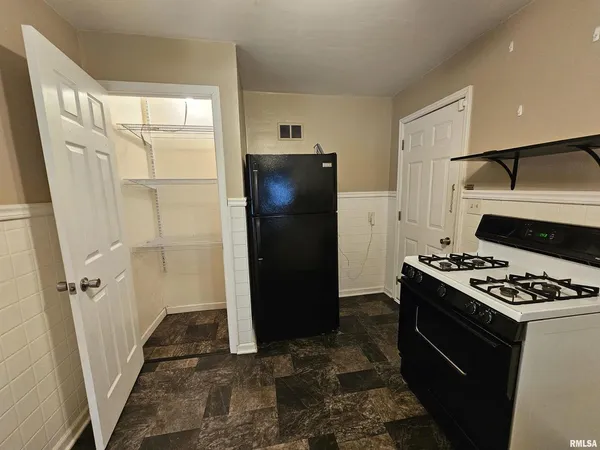 a view of kitchen with stainless steel appliances granite countertop a refrigerator and a stove