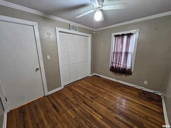 an empty room with wooden floor closet and windows