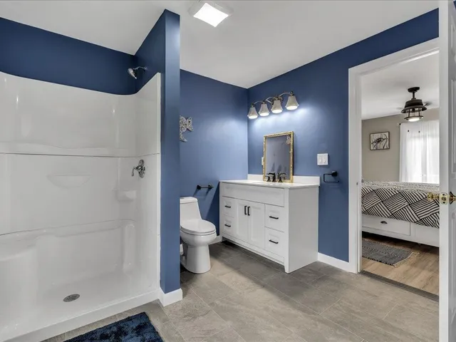 a en suite spacious bathroom with a double vanity sink a toilet and a mirror