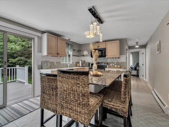 a kitchen with stainless steel appliances kitchen island granite countertop a stove a refrigerator a sink a dining table and chairs with the floor