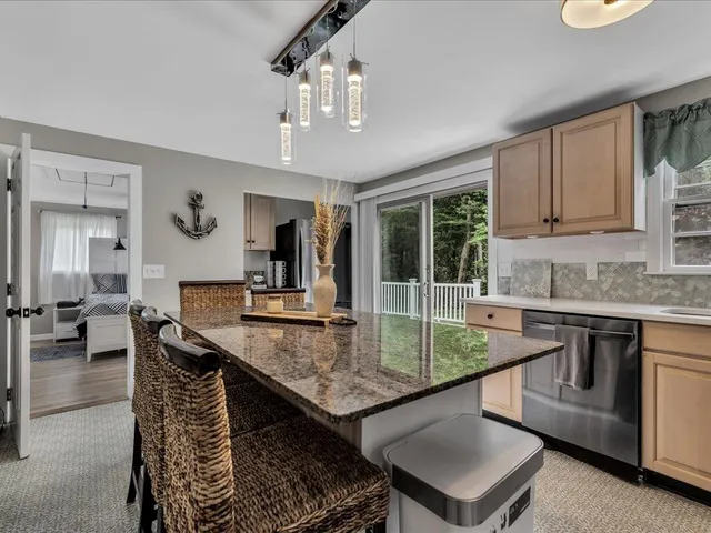 a dining hall with stainless steel appliances granite countertop a granite counter tops a stove a sink dishwasher a dining table and chairs with wooden floor