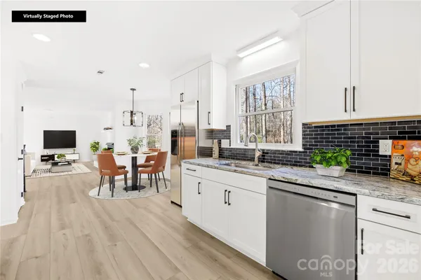 a kitchen with stainless steel appliances granite countertop a sink dishwasher a stove and a dining table with wooden floor